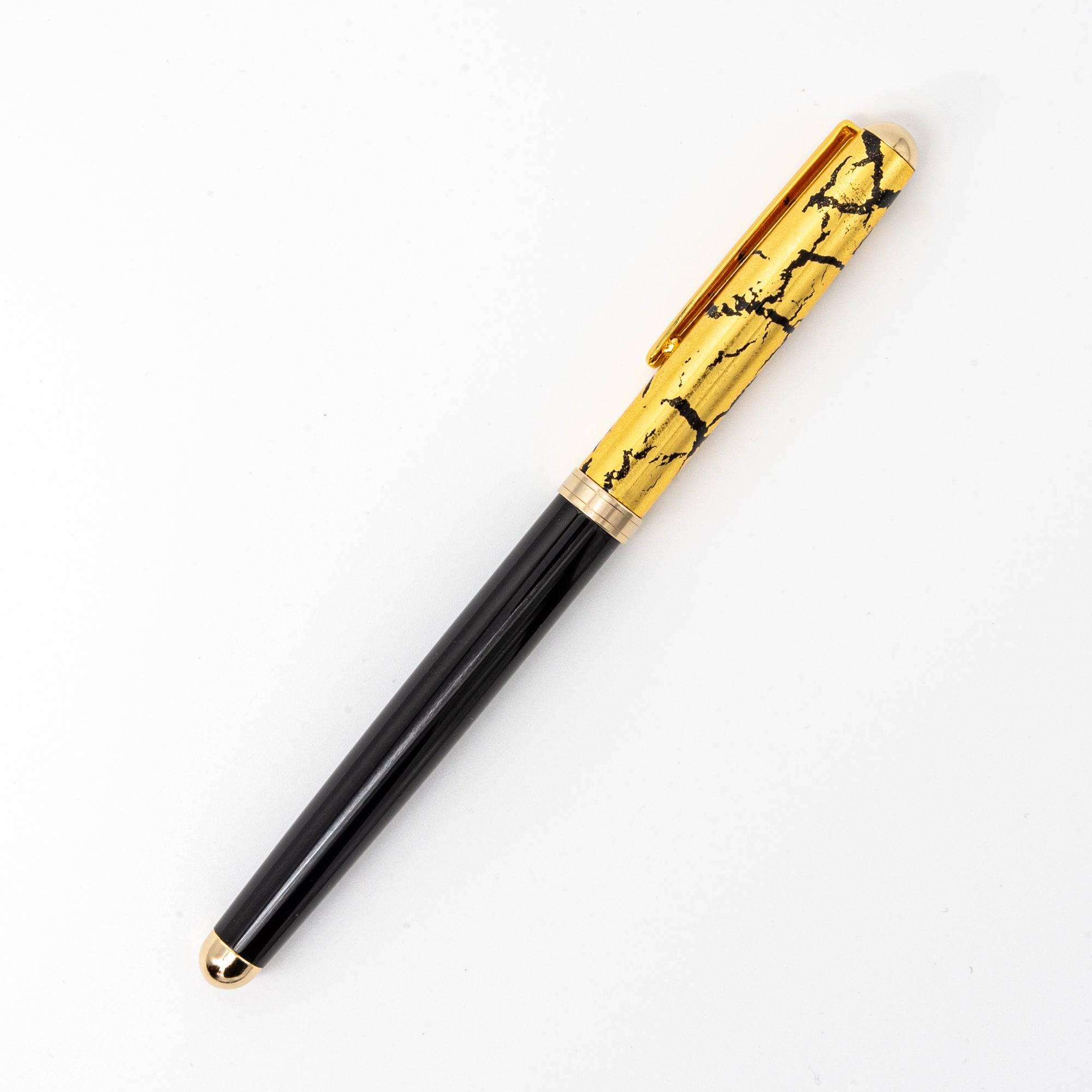 A black ballpoint pen with a gold crack pattern cap, featuring a minimalist and luxurious aesthetic, placed on a white background.