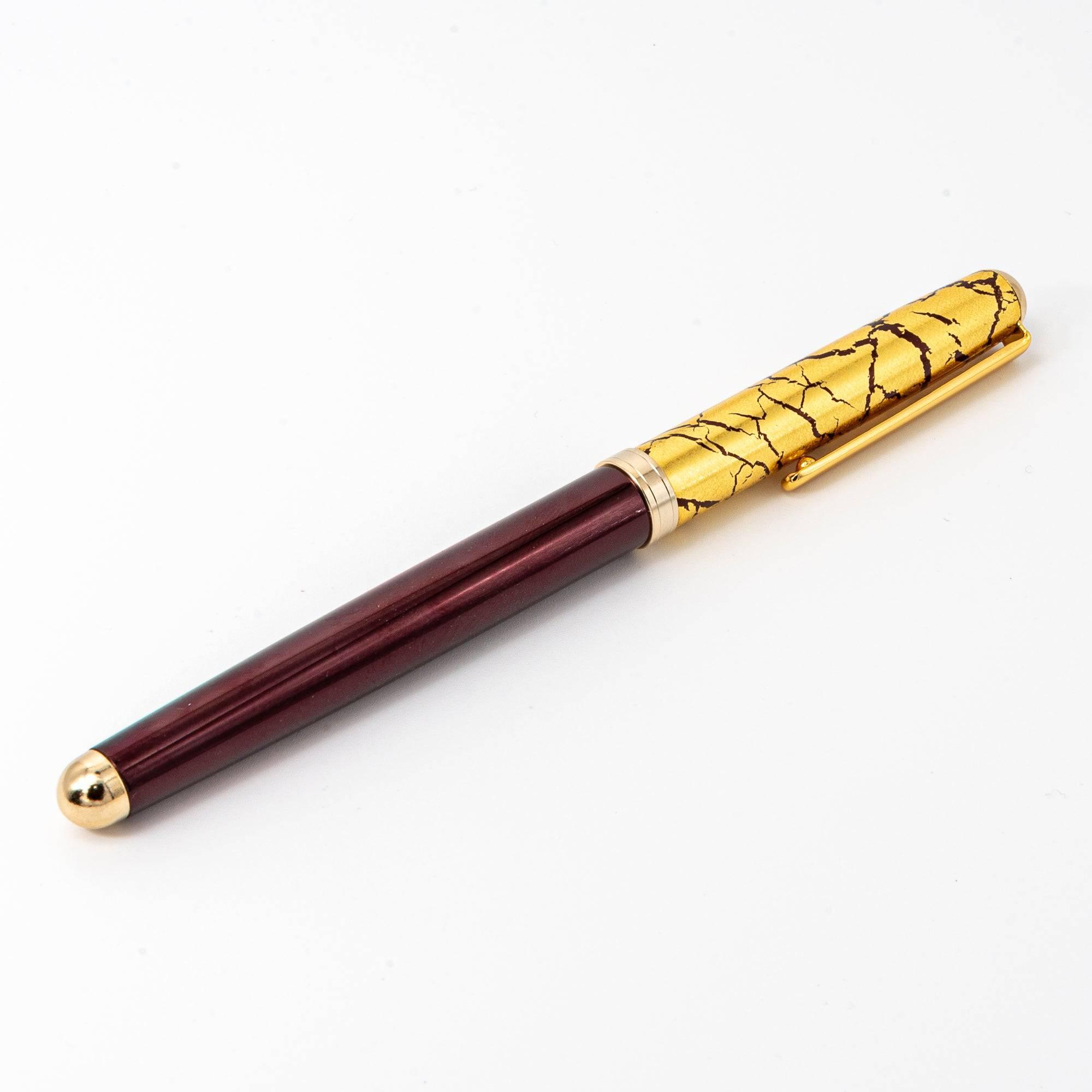 A closed wine-red ballpoint pen with a gold crack pattern cap, combining traditional craftsmanship and modern elegance.