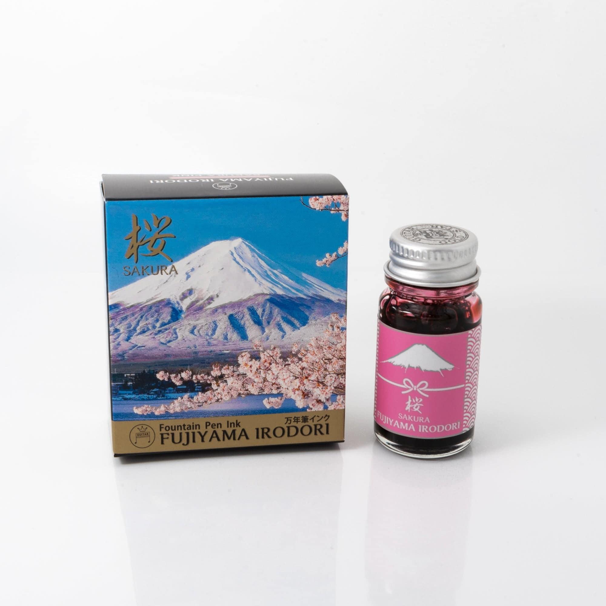 Fujiyama Irodori Sakura fountain pen ink bottle with a soft pink hue, placed on a wooden desk under gentle natural light.