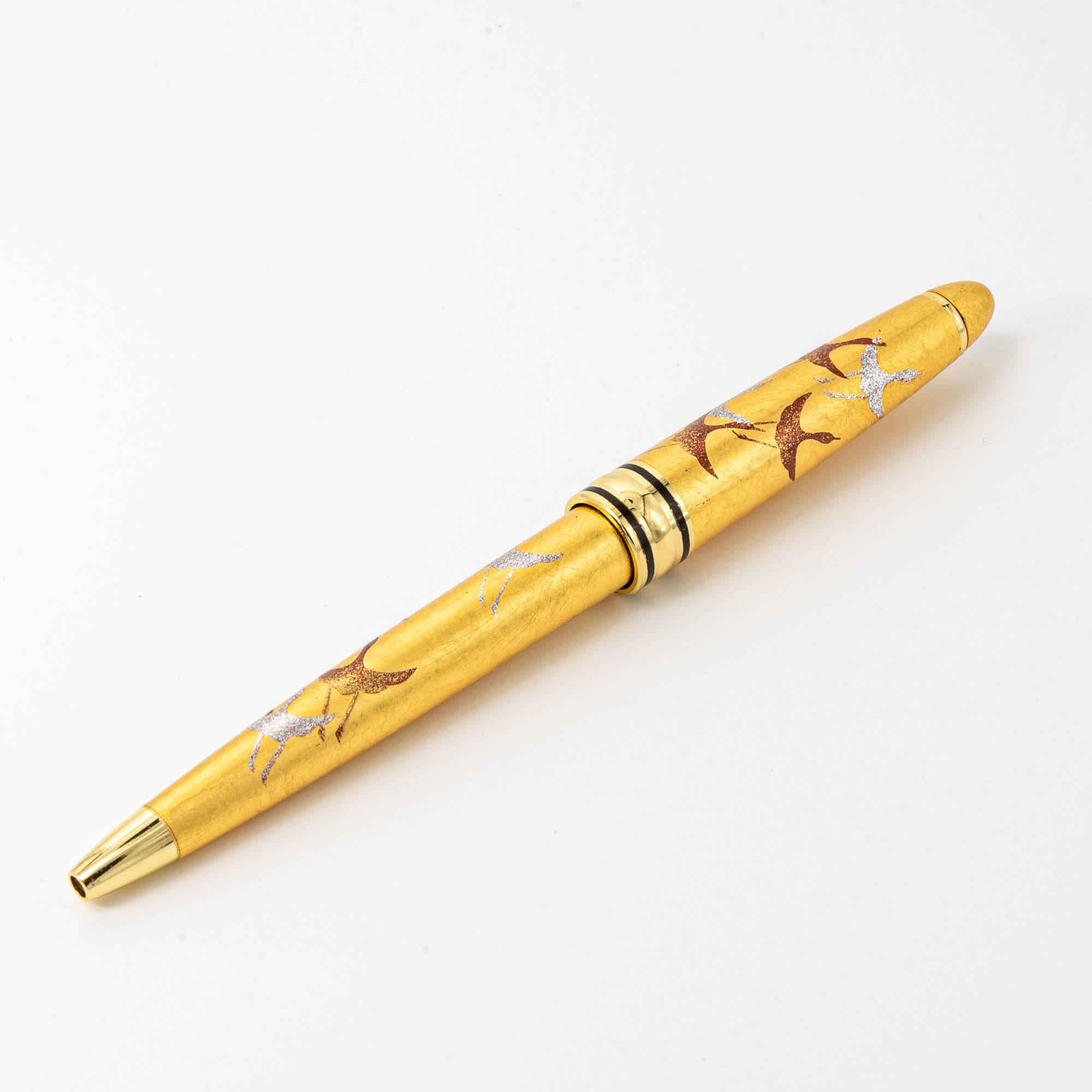 A close-up of the gold maki-e ballpoint pen showcasing its detailed crane artwork and elegant metallic finish.