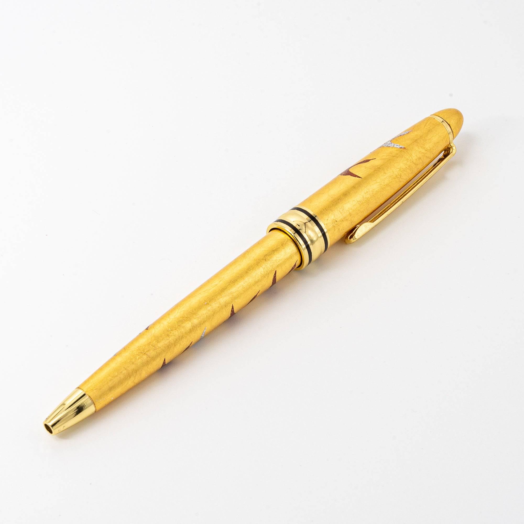 The gold maki-e ballpoint pen displayed on a white background, highlighting its sleek design and intricate crane patterns.