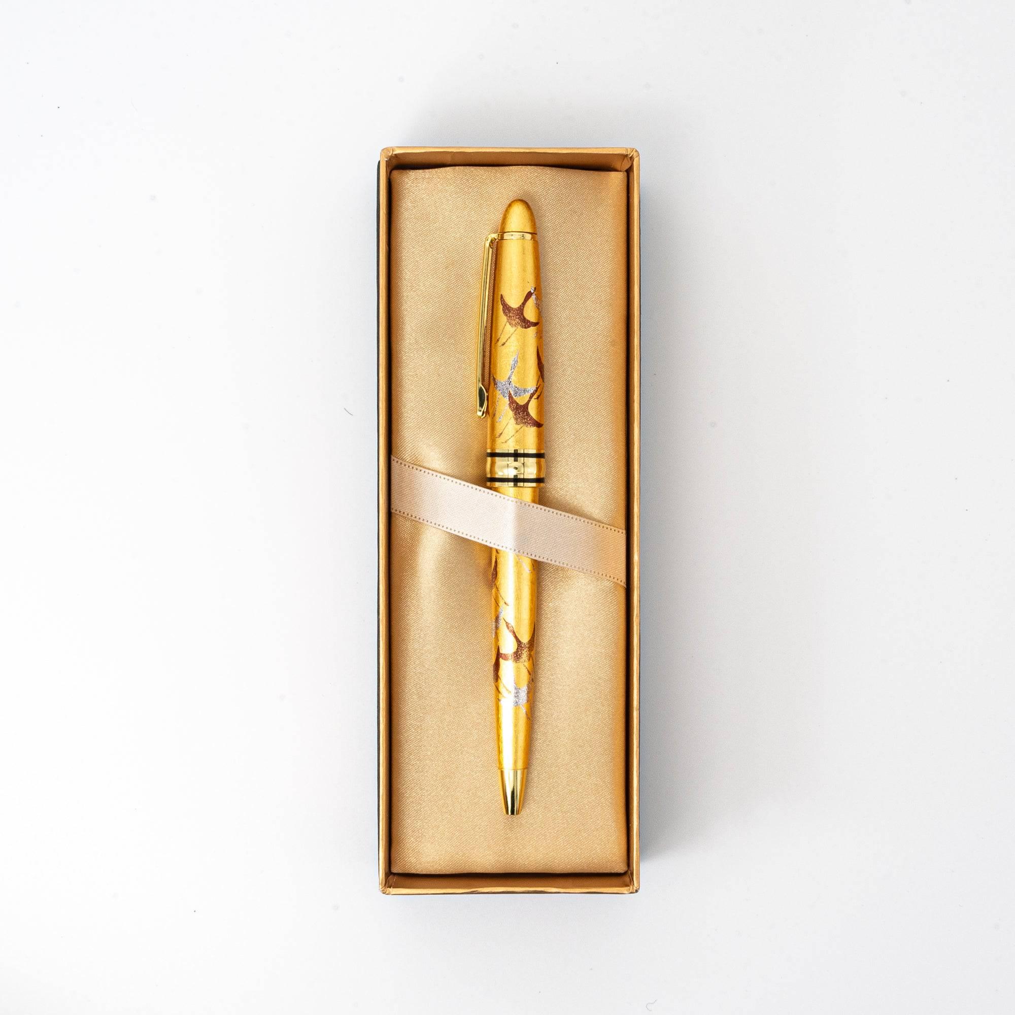 The gold maki-e ballpoint pen displayed in a luxurious box lined with satin, secured with an elegant ribbon.