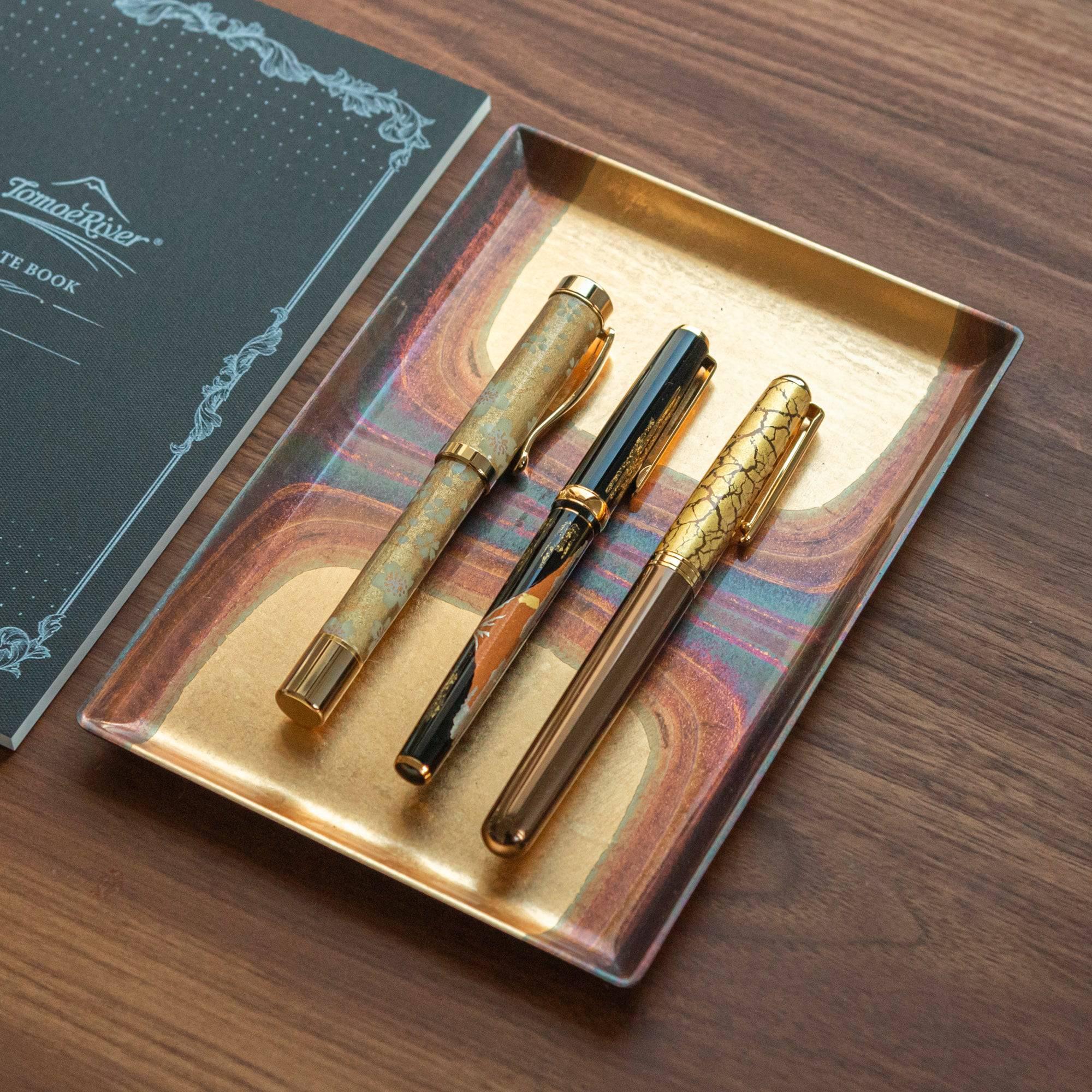 Set of three Japanese fountain pens, including Mt. Fuji maki-e, displayed on a gold tray to emphasize their elegant designs.