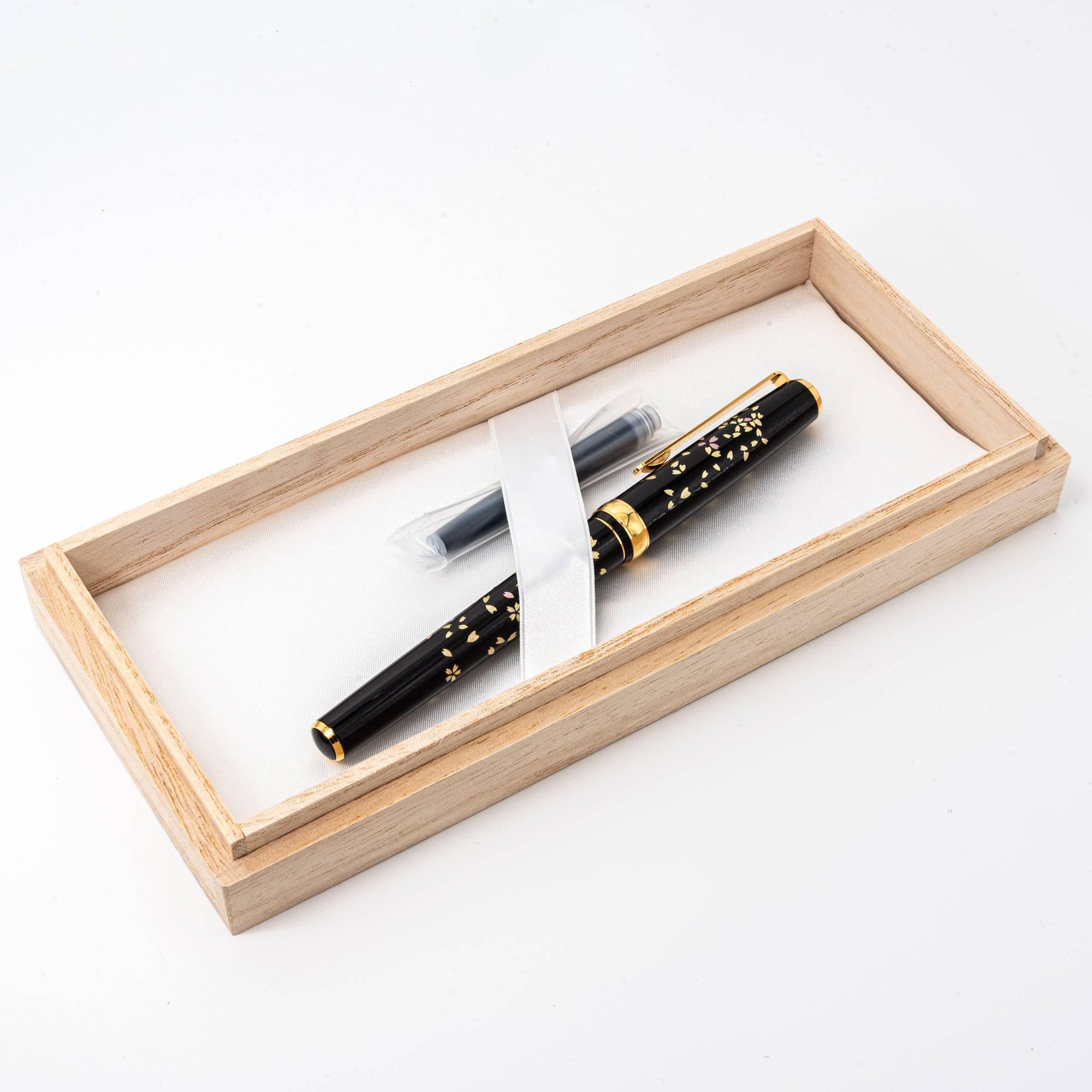 Japanese fountain pen with sakura design, black lacquer body, gold-plated nib, and wooden gift box, including ink cartridge. (123文字)