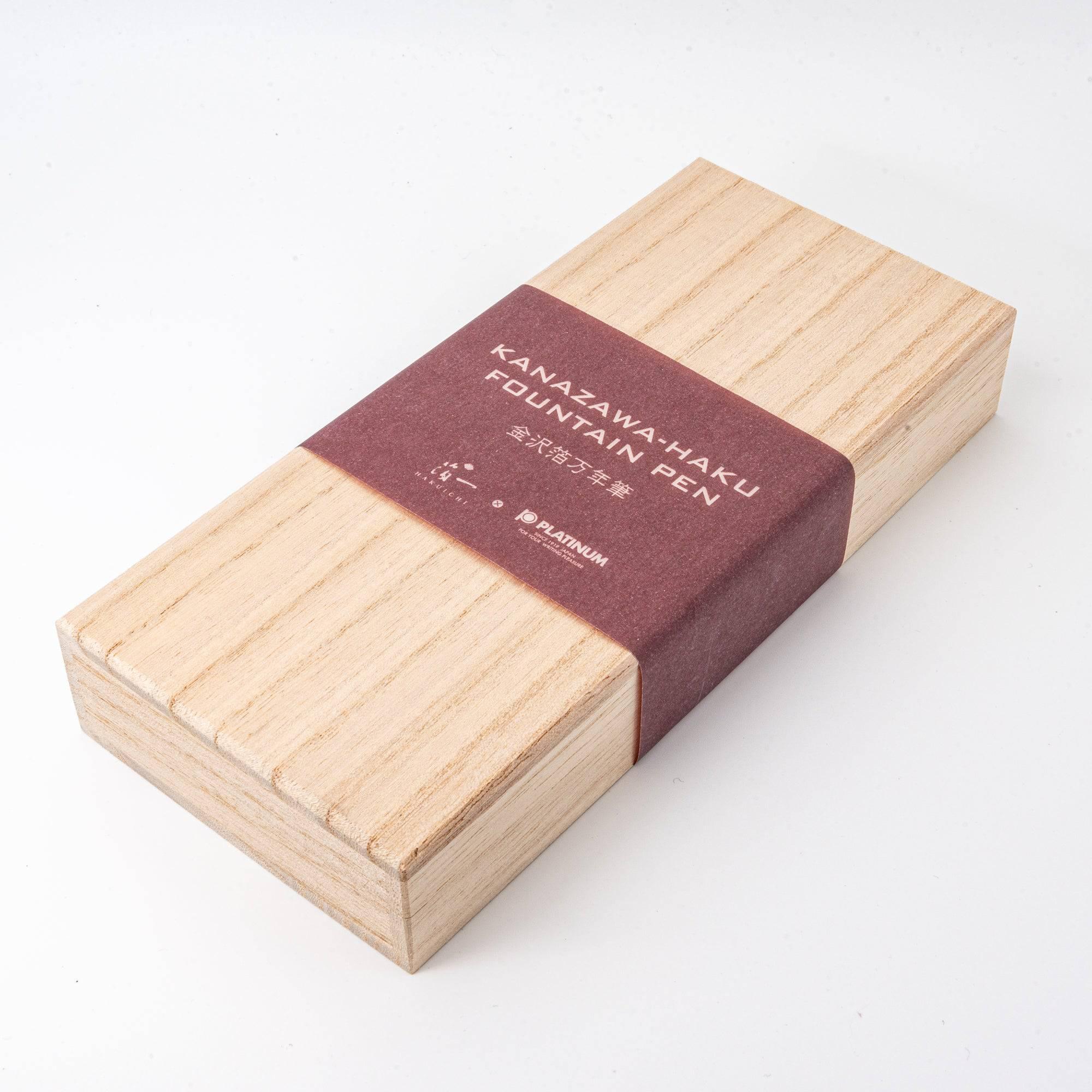 A detailed view of a wooden box's lid with the text "Kanazawa-Haku Fountain Pen" and branding, reflecting its premium presentation. (120 characters)