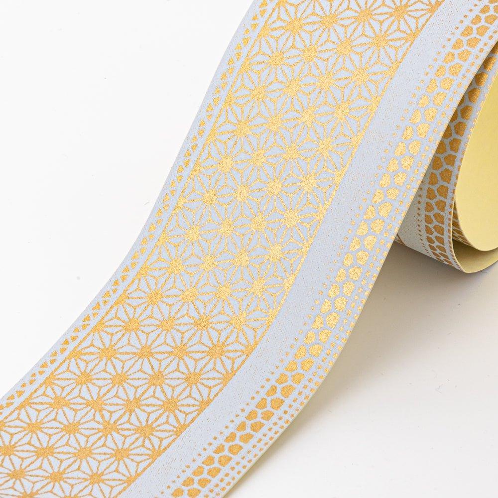 Close-up of Japanese stationery washi tape highlighting intricate gold geometric patterns and white details on a light surface.  