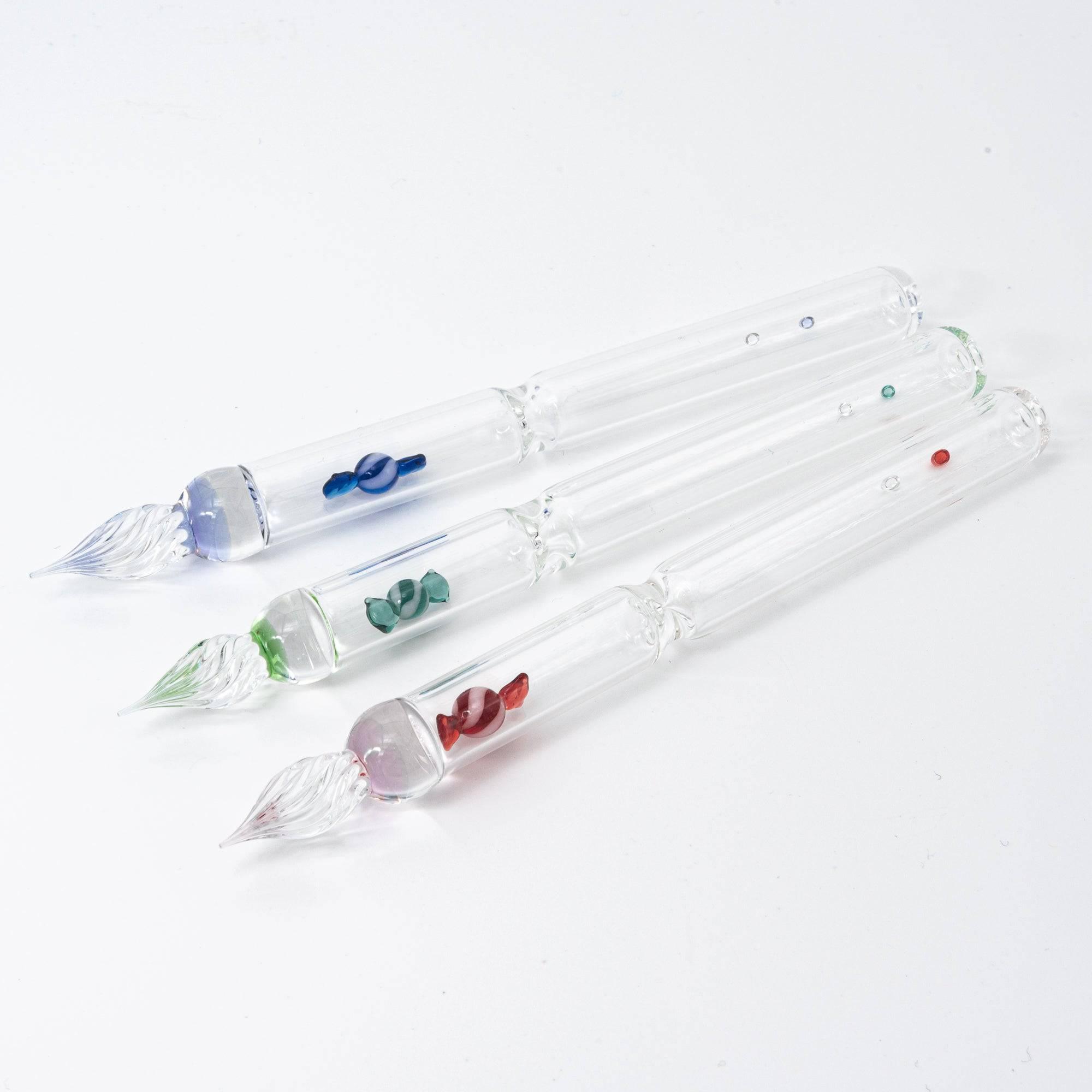 Three glass pens, each featuring a colorful candy motif in blue, green, and red, encased in the clear glass, bringing a fun twist to your writing tools.