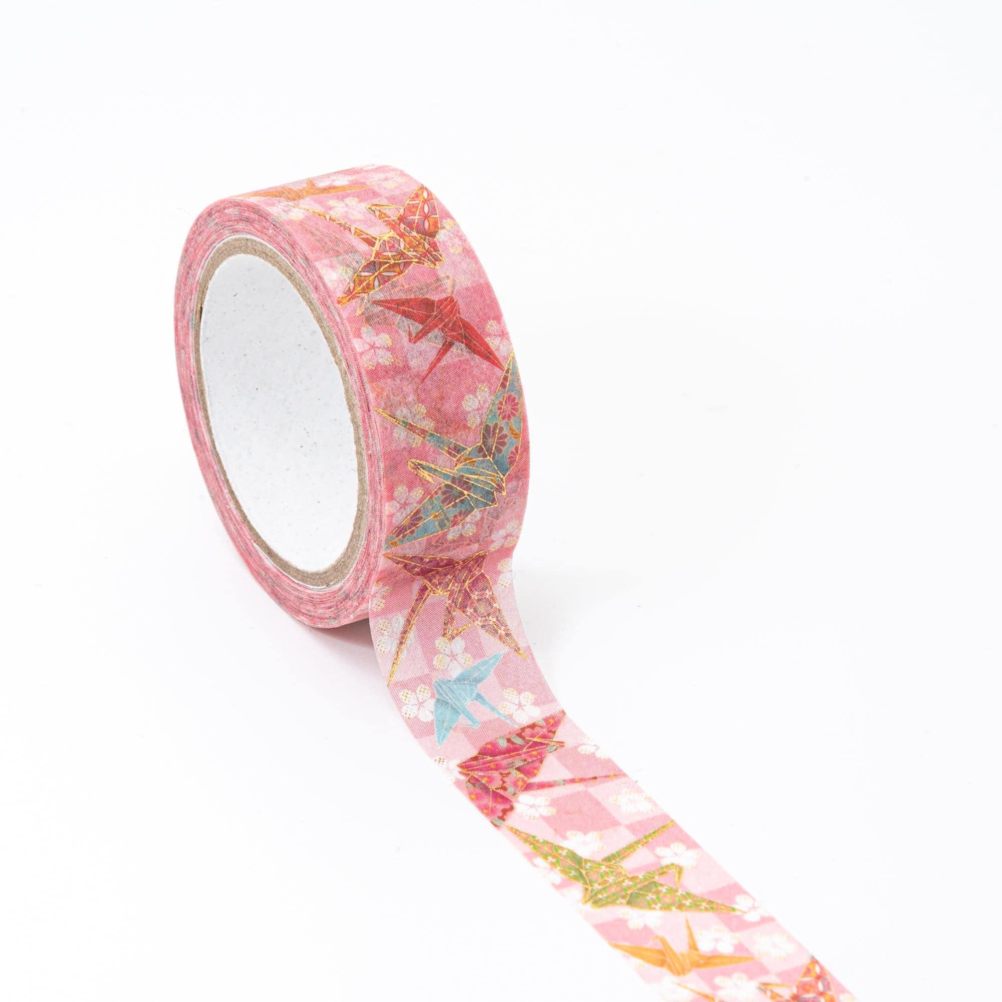 Roll of Iyo Washi Tape with origami crane designs, unraveling to reveal its artistic motifs, placed on a wooden surface under soft lighting.  