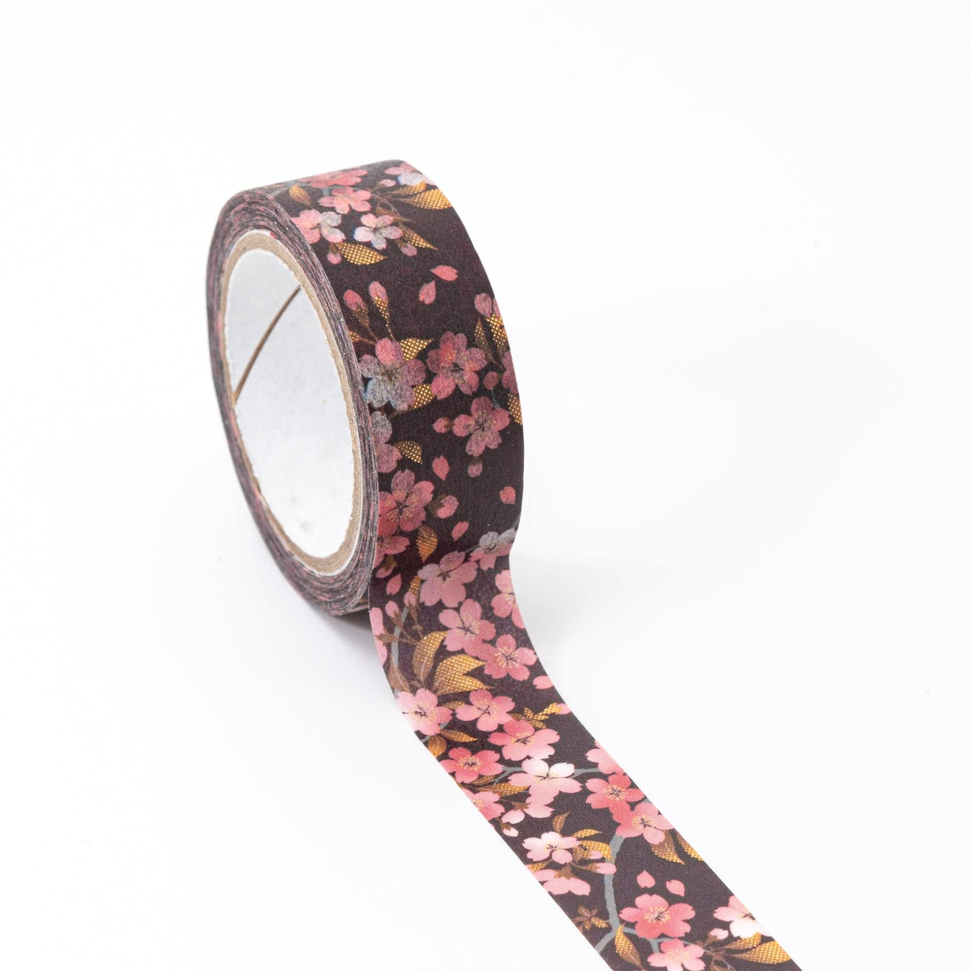 Roll of Iyo Washi Tape with sakura blossoms, unraveling to reveal intricate floral motifs, placed on a wooden surface under natural light.  