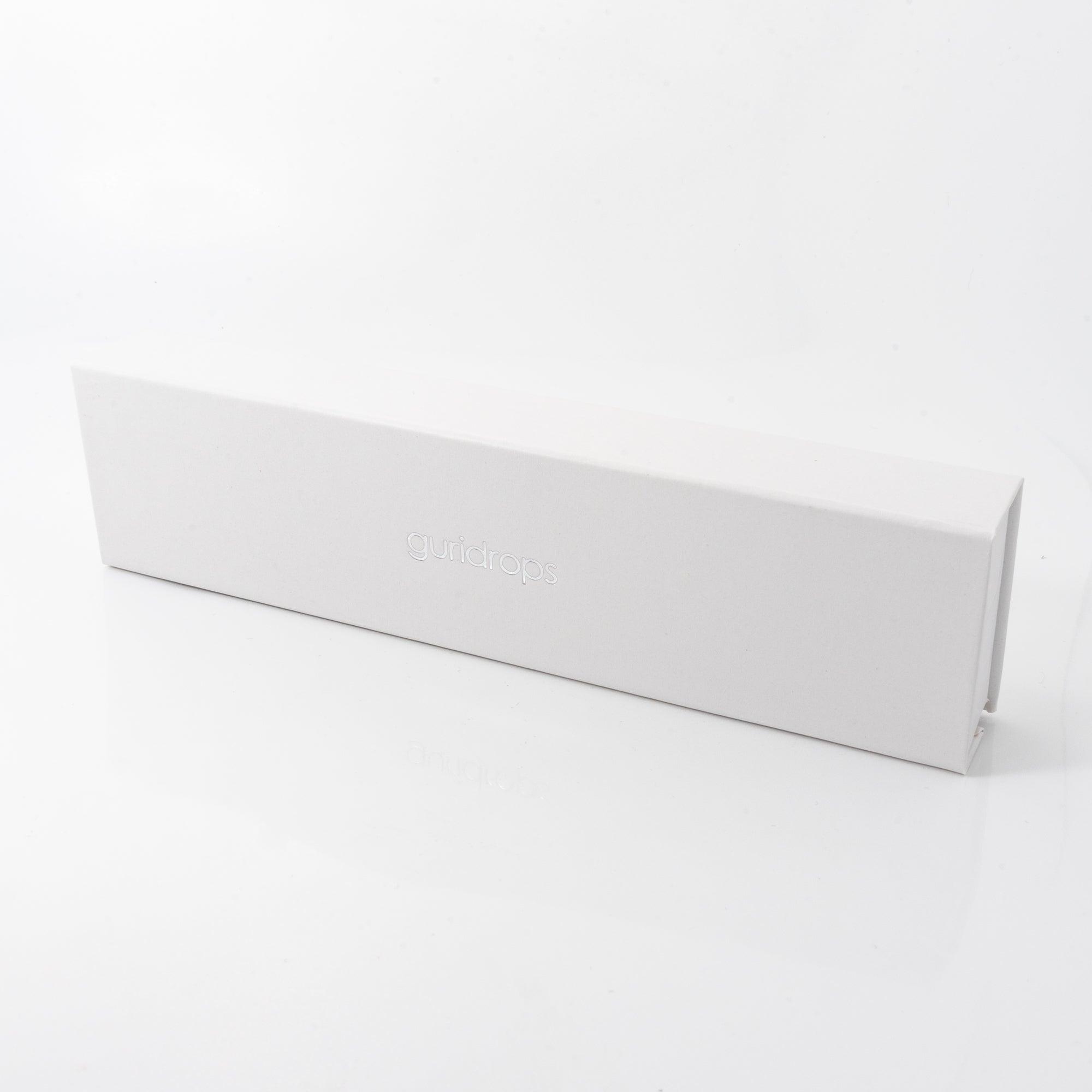 A simple, elegant white box with the "guridrops" logo embossed on it, used for packaging the glass pen.