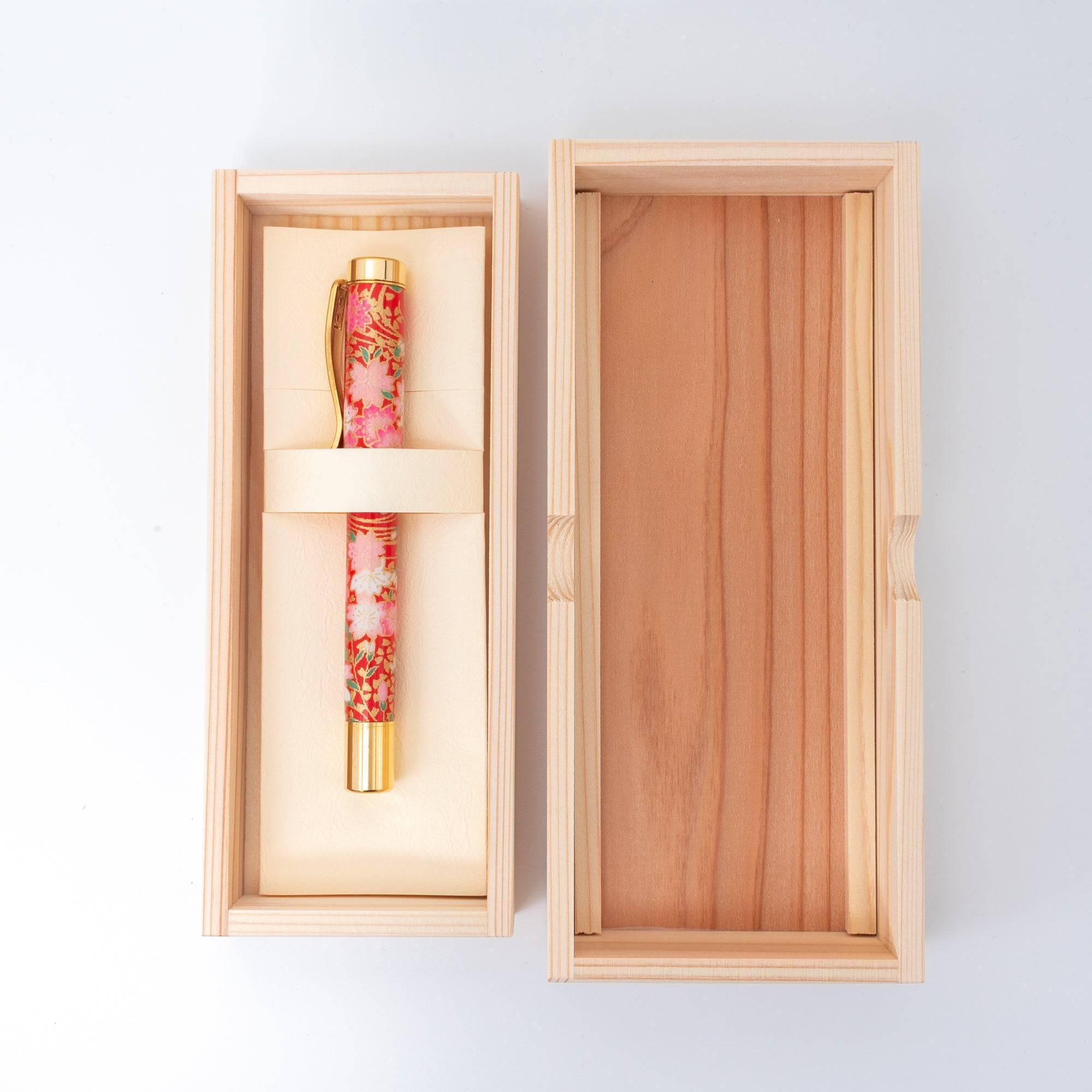 A Japanese fountain pen with a red floral design presented in a wooden box, highlighting its traditional craftsmanship and premium packaging.  