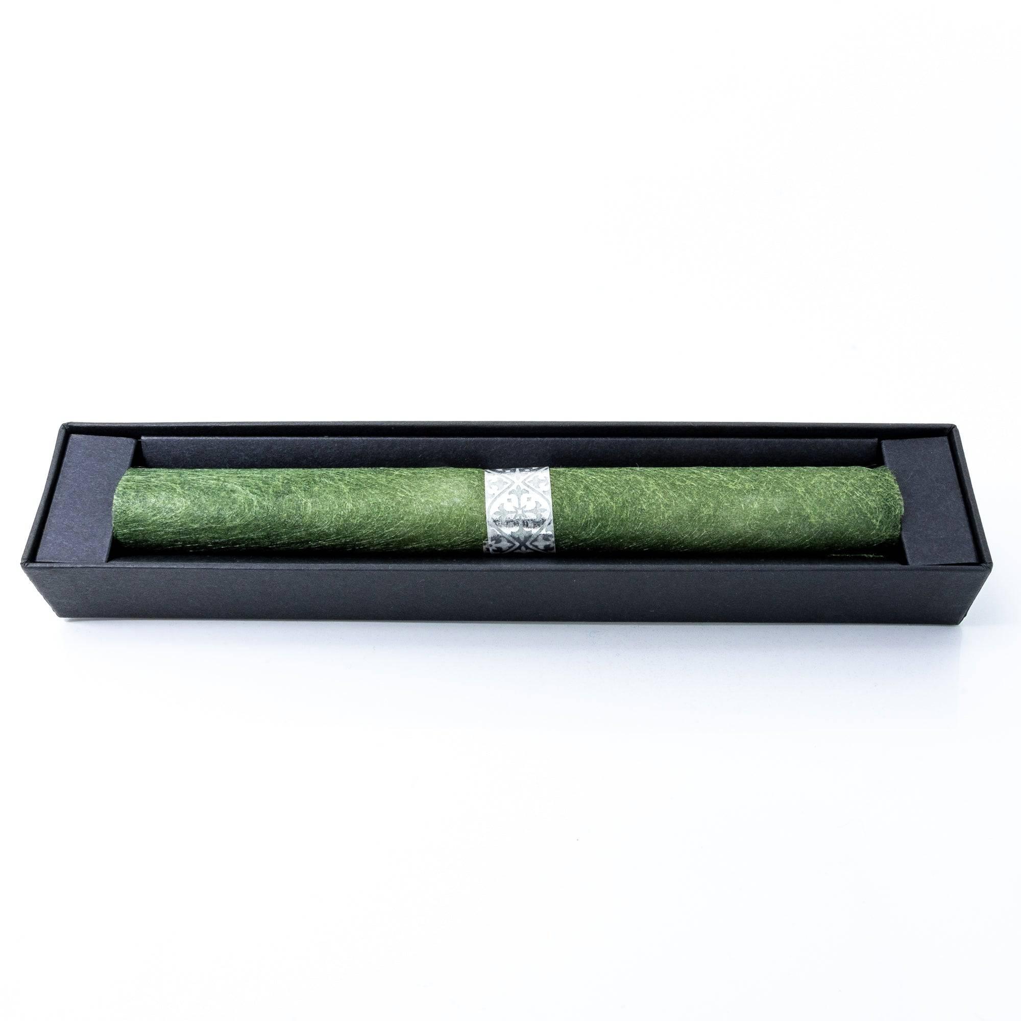 An elegant green-colored glass pen, carefully wrapped with a silver decorative band, inside a black box with 'Sourire' branding.