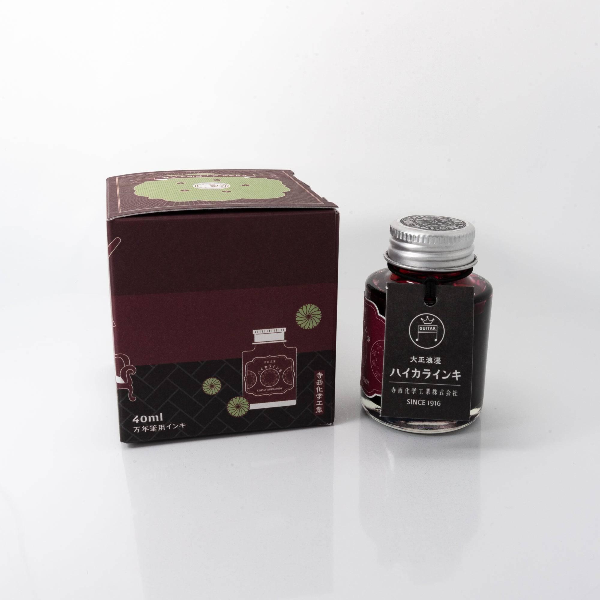 Open Taisho Romance Classy Burgundy ink bottle with bold burgundy liquid, placed beside a fountain pen, blending style and functionality.  