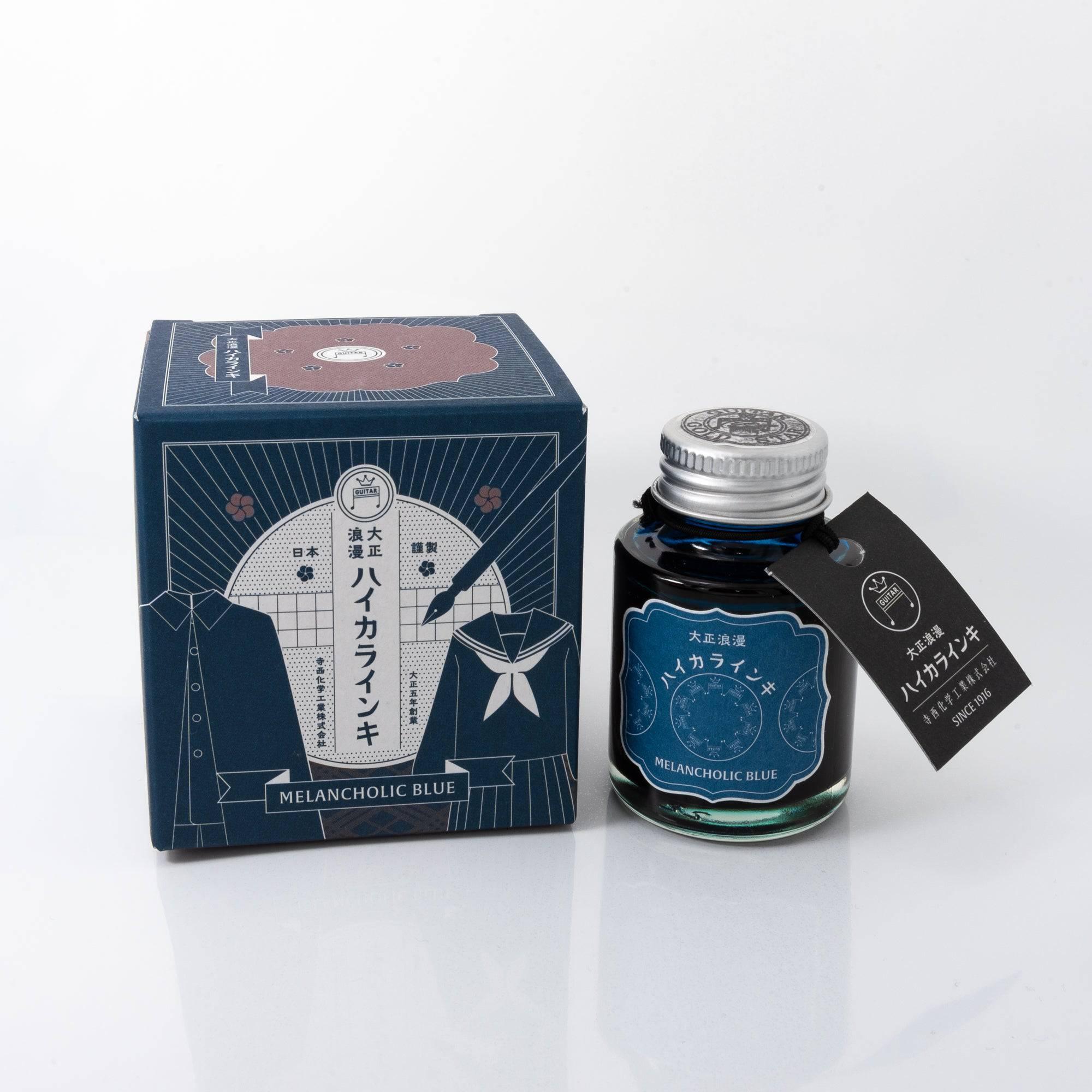 Taisho Romance Melancholic Blue fountain pen ink bottle with a deep blue hue, placed on a wooden desk under soft natural light.  