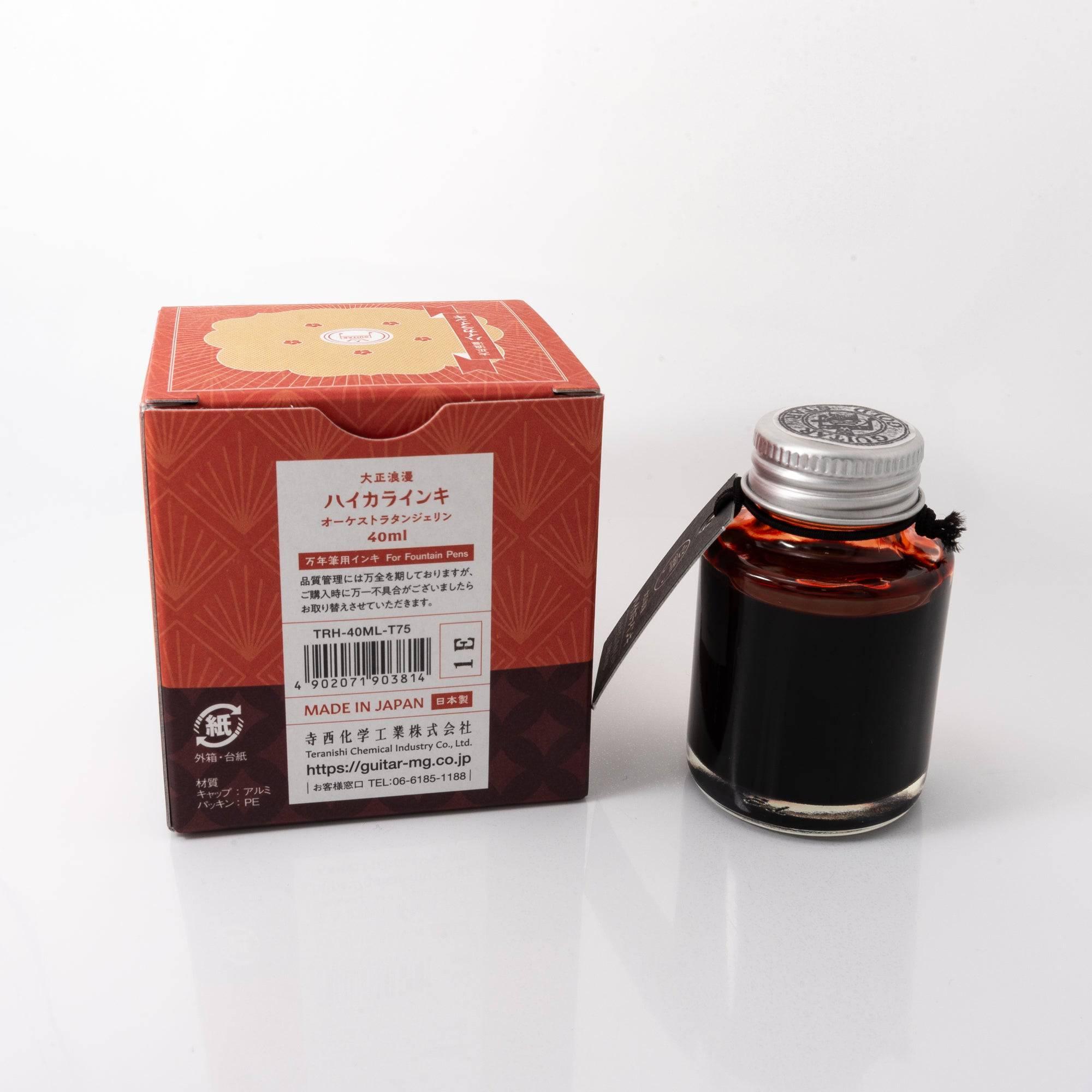 Top view of the Taisho Romance Orchestra Tangerine ink bottle, highlighting its vivid orange ink, surrounded by natural wooden tones.  