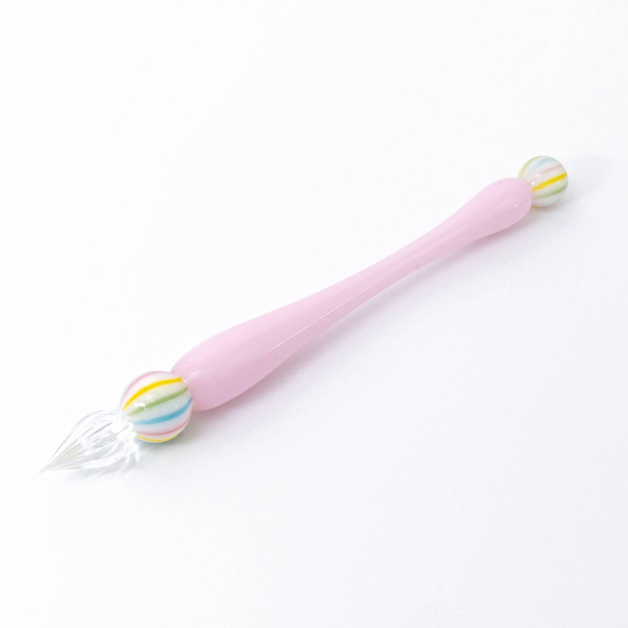 A pink glass pen inspired by traditional Japanese wagashi, featuring pastel-colored, marble-like glass beads at each end for a delicate and playful aesthetic.