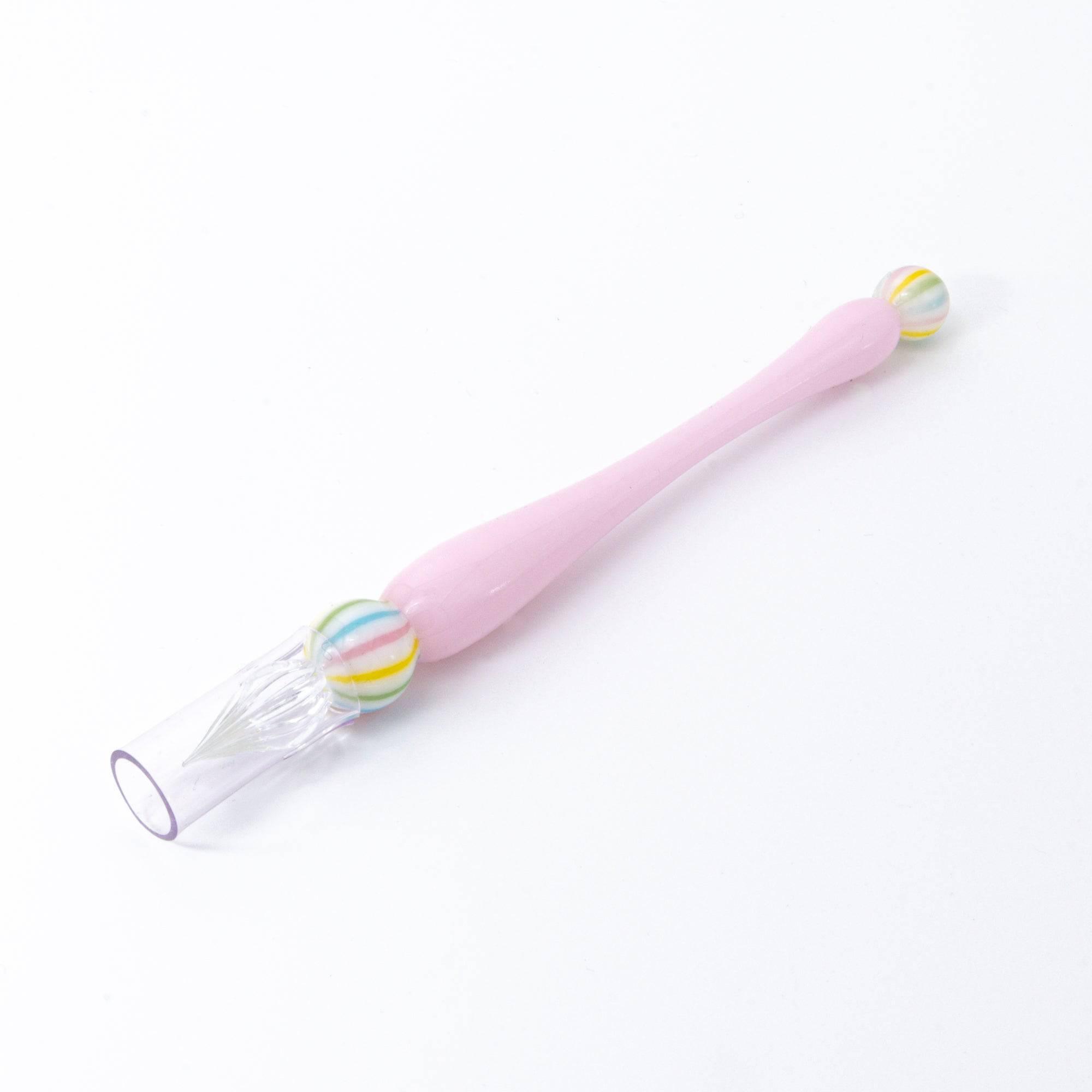 A pink glass pen inspired by traditional Japanese wagashi, featuring pastel-colored, marble-like glass beads at each end for a delicate and playful aesthetic.