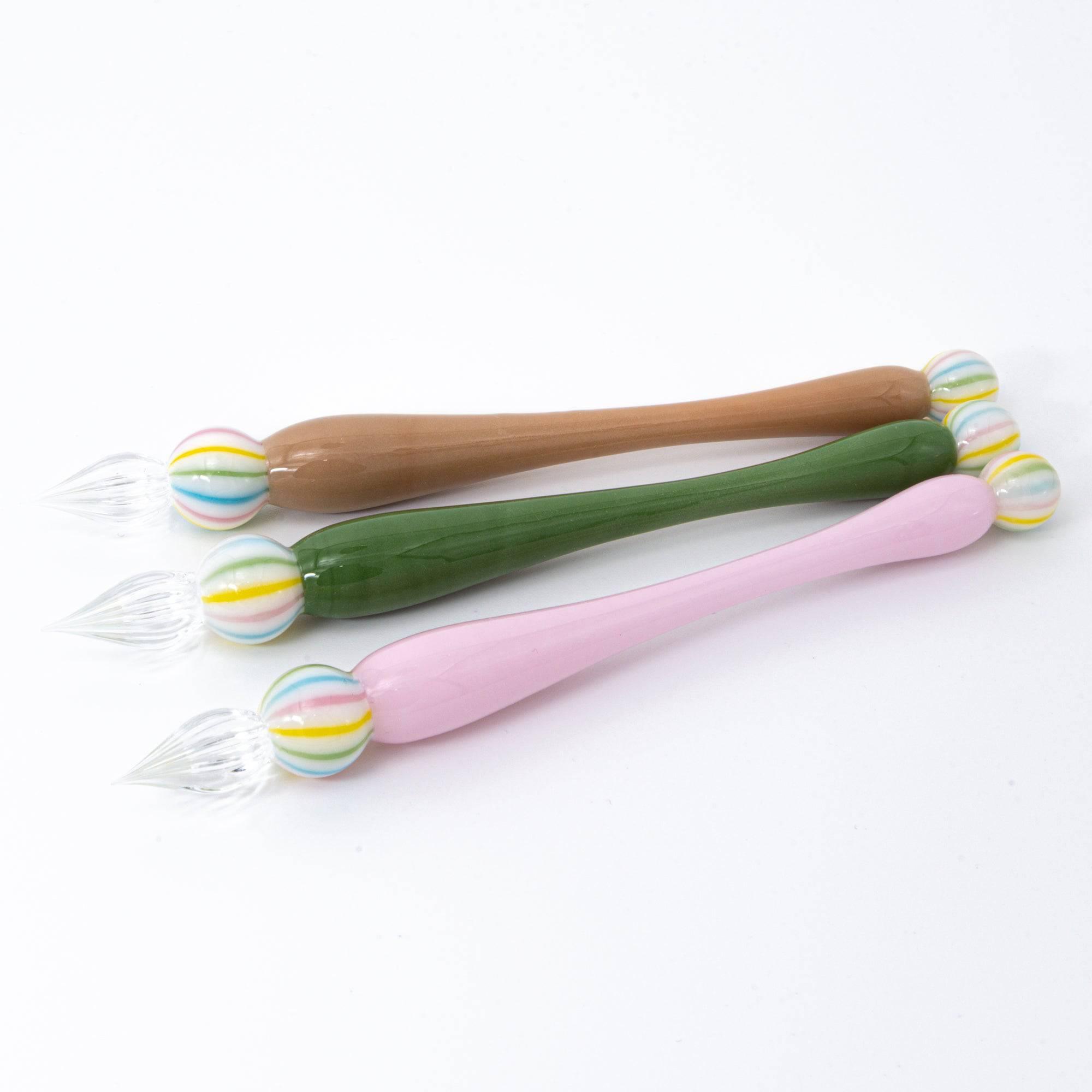 Three glass dip pens with pastel-colored handles and marble-like tops, inspired by Japanese wagashi, arranged in a row on a white background.