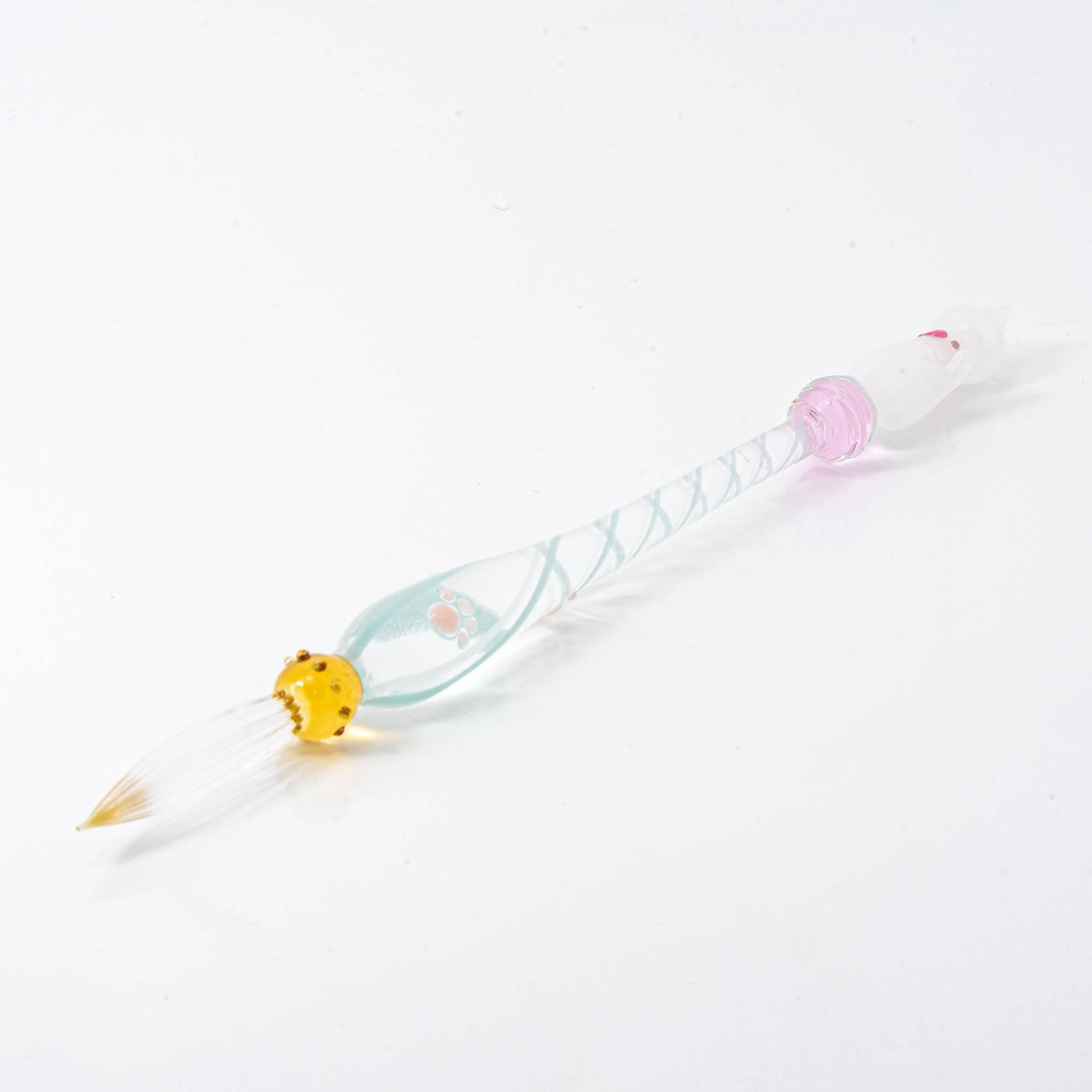 A delicate white glass pen featuring a cat design at the top and a twisted, clear handle, creating a whimsical and elegant look.